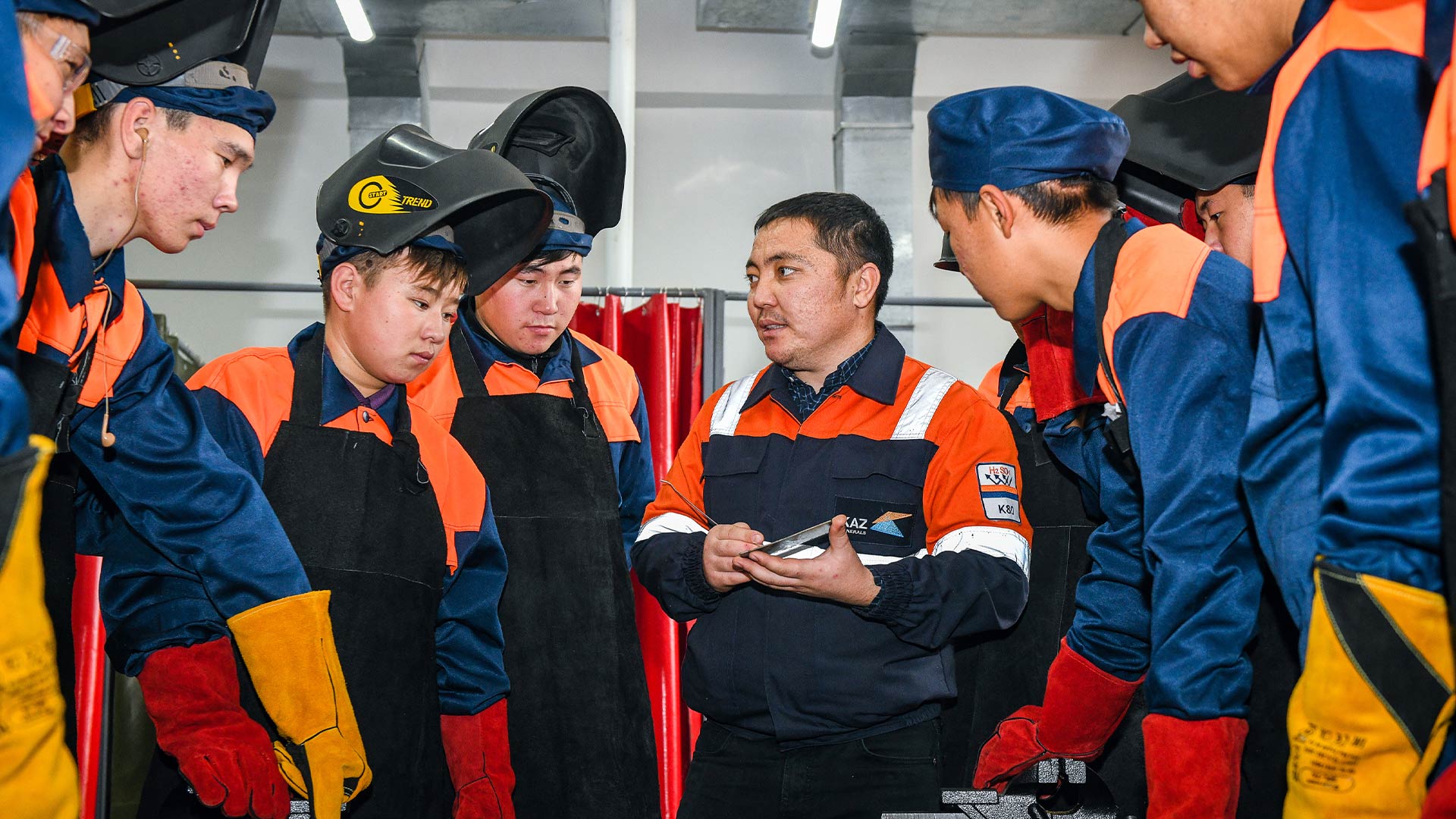 Несколько рабочих собрались вокруг и что-то обсуждали. На них были защитная одежда и головные уборы.