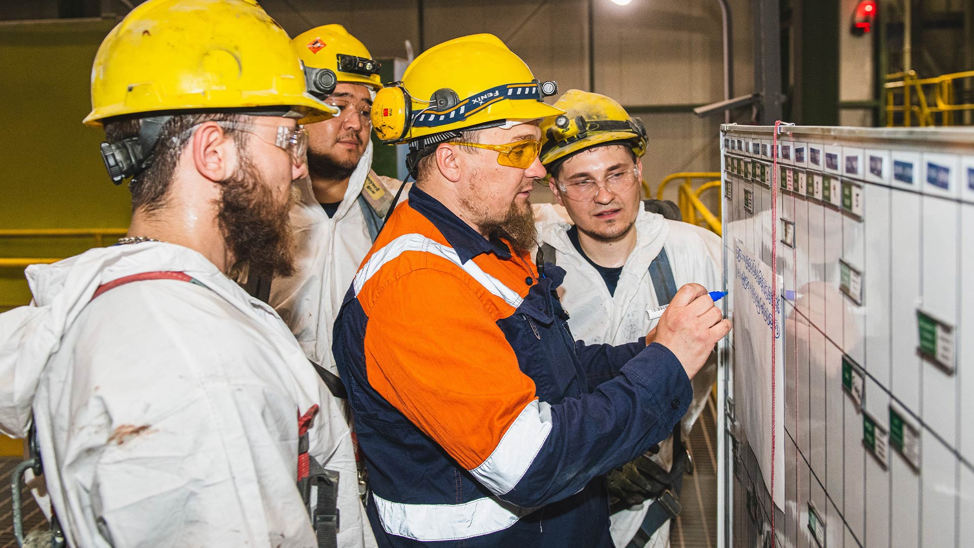 Несколько рабочих собрались вокруг белой доски.